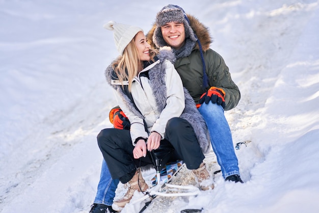 Couple s'amusant avec un traîneau sur la neige dans la neige de l'hiver. photo de haute qualité