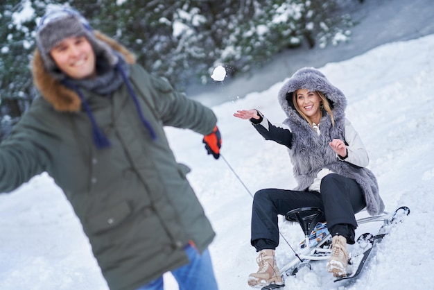 Couple s'amusant avec un traîneau sur la neige dans la neige de l'hiver. photo de haute qualité