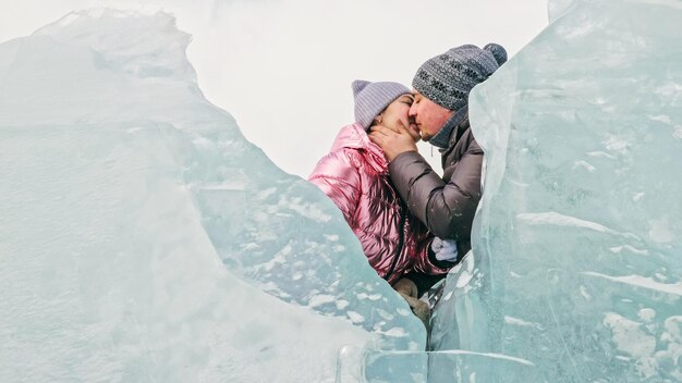 Un couple s'amuse à marcher en hiver sur fond de glace d'un lac gelé Les amoureux s'allongent sur une glace claire avec des fissures s'amusent à s'embrasser et à s'embrasser