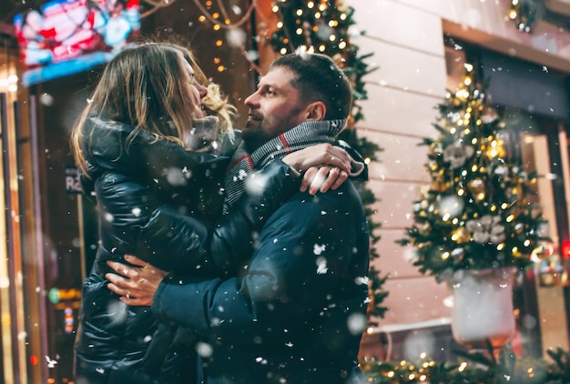 Un couple s'amuse en se tenant contre des bâtiments la nuit pendant l'hiver en ville.