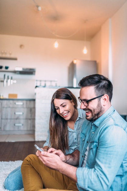 Couple s&#39;amuser à la maison. Jouer à des jeux sur le smartphone.