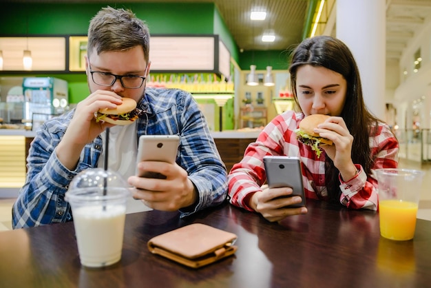 Un couple s'assoit au café et regarde dans son téléphone