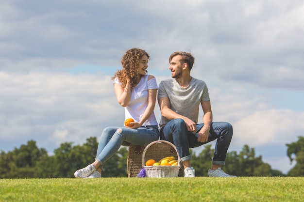 Le couple s'assoit sur le sac sur l'herbe