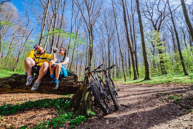 Photo un couple s'assoit sur une souche se reposant après avoir fait du vélo en forêt