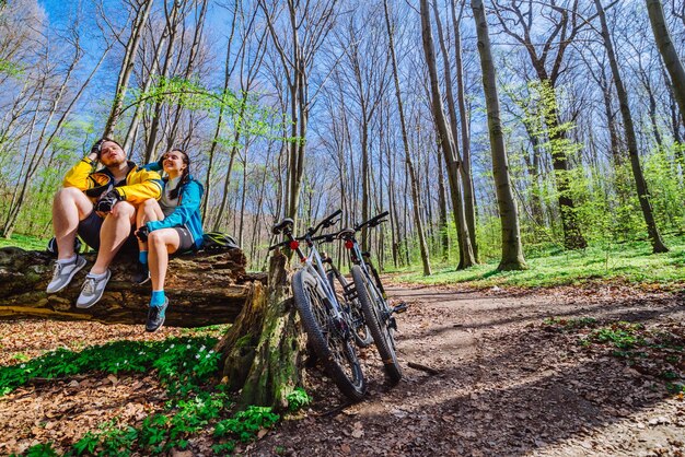Photo un couple s'assoit sur une souche se reposant après avoir fait du vélo en forêt
