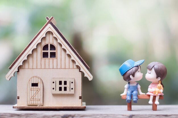 Couple s&#39;embrassant assis sur le banc de bois à côté de leur maison