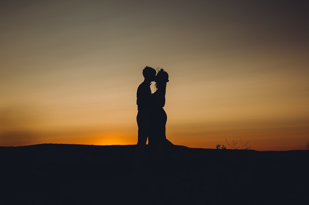 Couple s'embrassant au coucher du soleil.