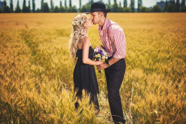 Couple s'embrassant avec bouquet debout sur un champ de blé