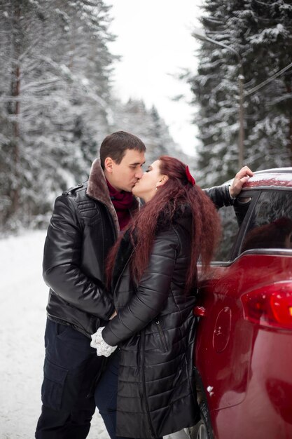 Photo couple s'embrassant dans la forêt d'hiver