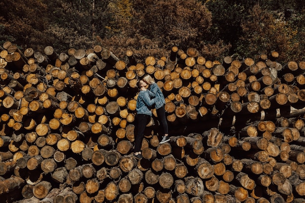 Couple s'embrassant et debout sur la pile de bois de chauffage dans la belle forêt d'automne colorée.