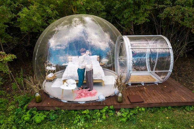 Un couple s'embrassant à l'intérieur d'une tente à bulles transparente au glamping