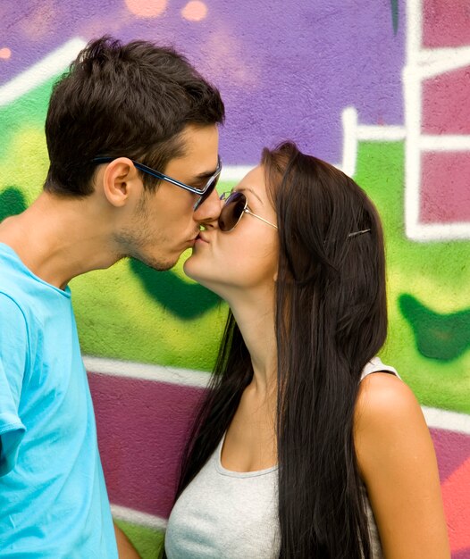 Couple s'embrassant près du mur de graffitis.