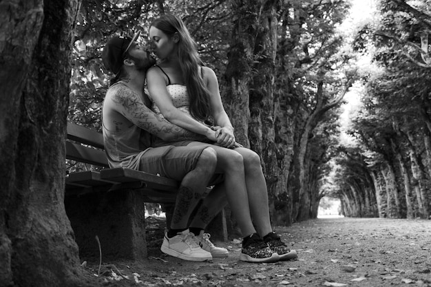 Photo un couple s'embrasse assis sur un banc dans le parc.