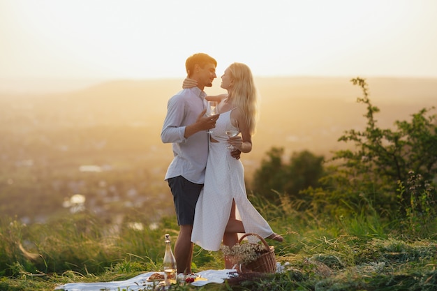 le couple s'embrasse et boit du vin au pique-nique d'été