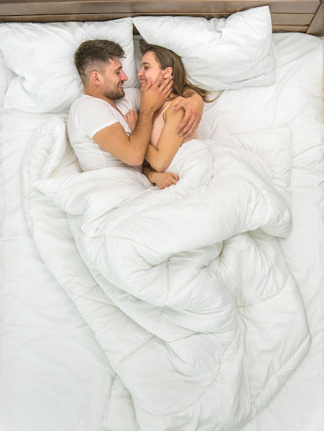 Photo le couple s'embrasse dans les draps blancs. vue d'en-haut