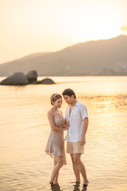 Le couple s'embrasse et se regarde sur la plage au coucher du soleil, moment romantique.