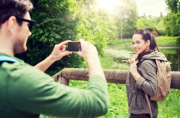 Photo un couple avec des sacs à dos prenant une photo avec un smartphone