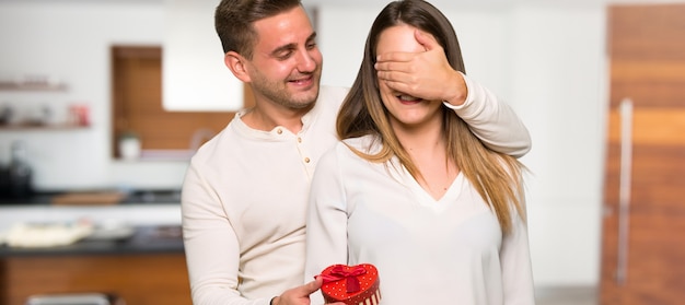 Couple à la Saint-Valentin tenant une boîte-cadeau dans une maison