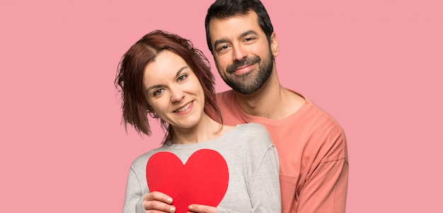 Couple à la Saint-Valentin tenant un symbole du coeur sur fond rose isolé