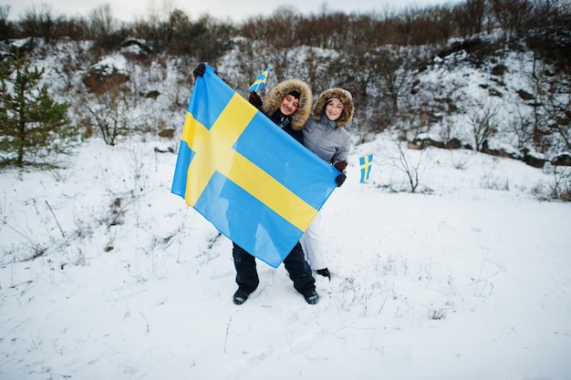 Couple scandinave avec le drapeau de la Suède dans le paysage suédois d'hiver.