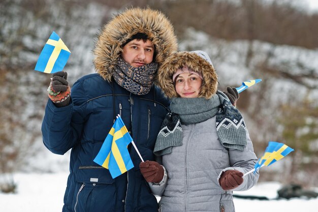 Couple scandinave avec le drapeau de la Suède dans le paysage suédois d'hiver.