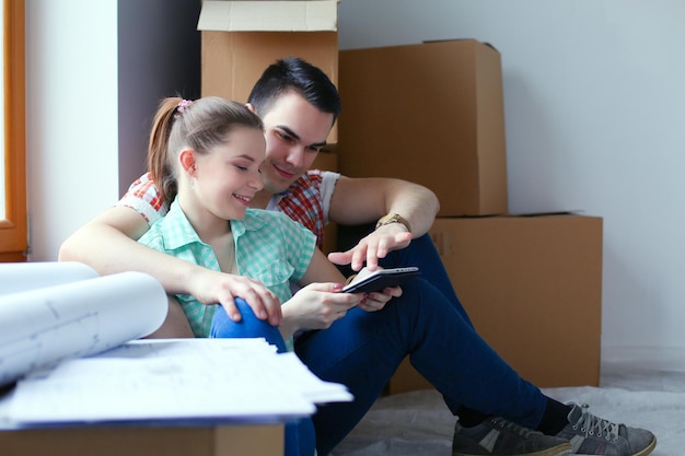 Couple se déplaçant dans la maison assis sur le sol avec ipad