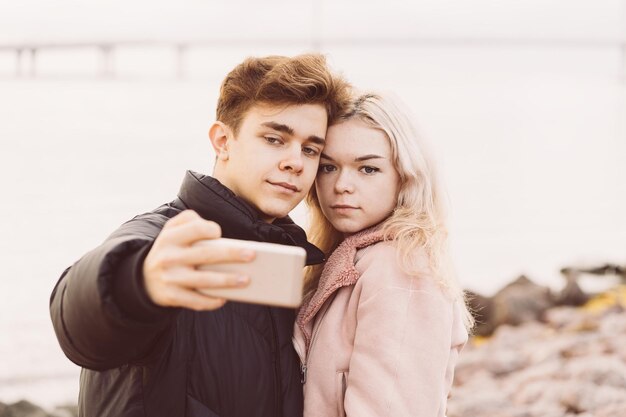 Un couple se fait un selfie avec son smartphone contre la mer.