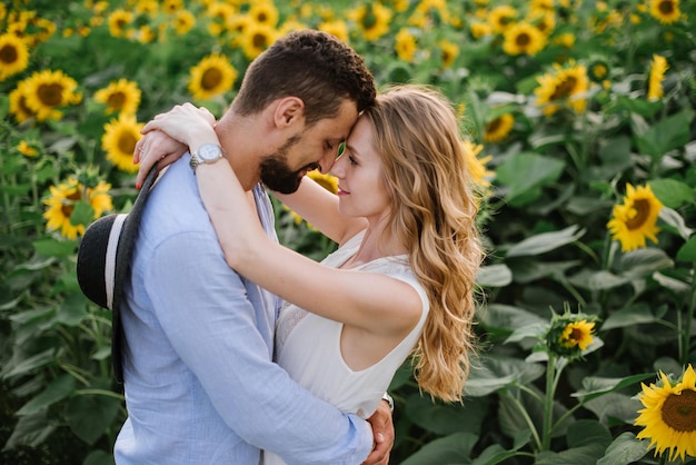 Un couple se promène dans les tournesols dans un champ un jour d'été