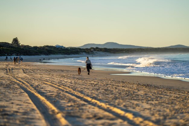 Un couple se promène sur la plage. Des femmes en manteaux et chapeaux marchent sur une plage d'hiver à Hobart, en Tasmanie, en Australie, au printemps.