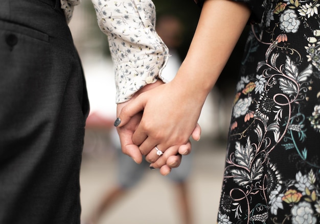 Un couple se tenant la main, l'un d'eux porte une bague.