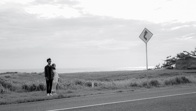 Photo un couple se tient sur le bord d'une route avec un panneau indiquant 