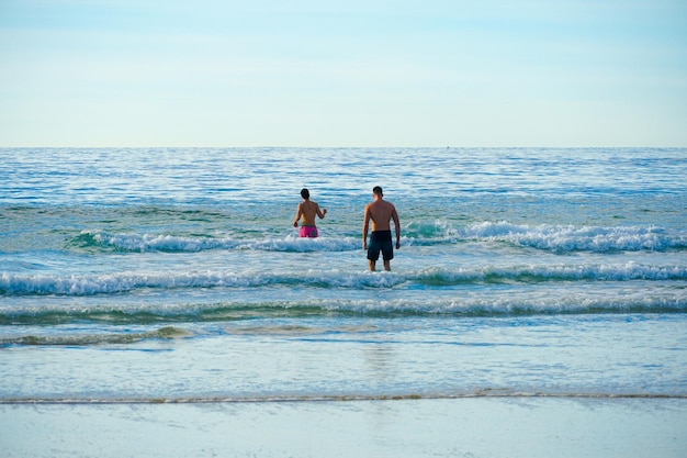 Un couple se tient dans l'océan, l'une des nombreuses vagues qui est sur le point de se jeter dans l'océan.