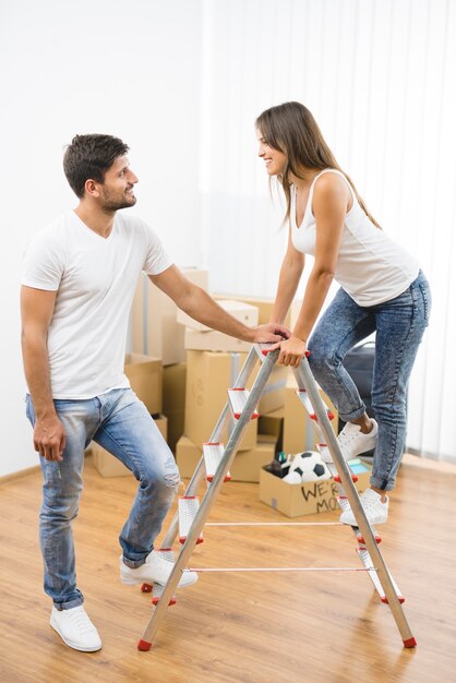 Le couple se tient sur l'échelle sur le fond des boîtes en carton