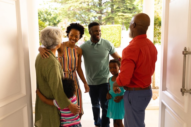 Photo couple senior afro-américain accueillant sa famille tout en se tenant sur la porte d'entrée de la maison