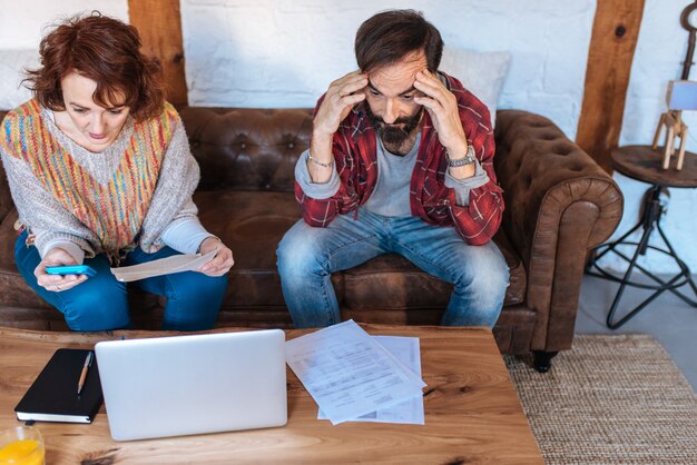 Couple senior assis à la maison en regardant leurs problèmes financiers