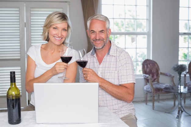 Couple senior grillage des verres à vin à la maison