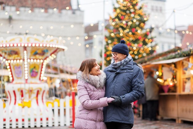 Un couple de seniors heureux s'embrassant au marché de Noël.