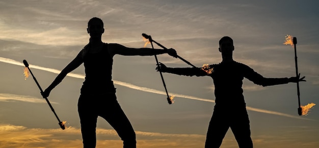 Photo un couple sexy d'artistes de feu manipule des matraques enflammées dans les tons du soir sur un ciel idyllique en plein air nature