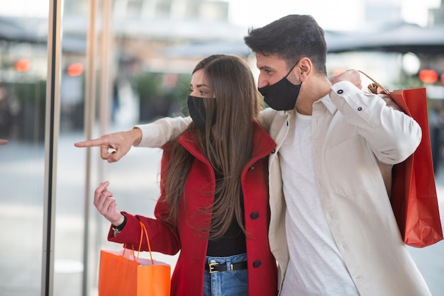 Couple de shopping covid et coronavirus marchant dans une ville tout en portant des sacs à provisions