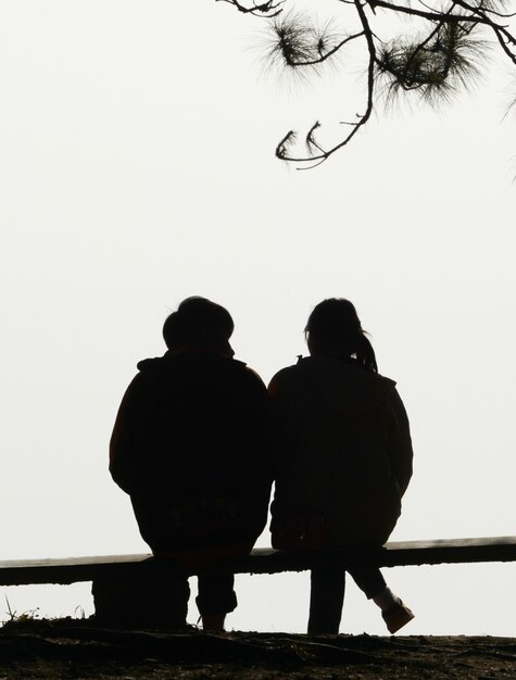 Photo couple de silhouette aime assis sur un banc