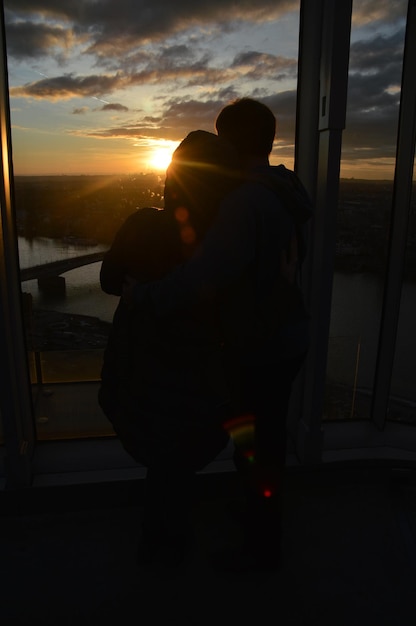 Photo un couple de silhouettes assis contre la mer au coucher du soleil