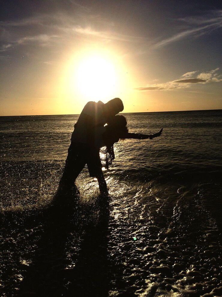 Photo un couple de silhouettes s'embrassant sur le rivage contre le ciel au coucher du soleil