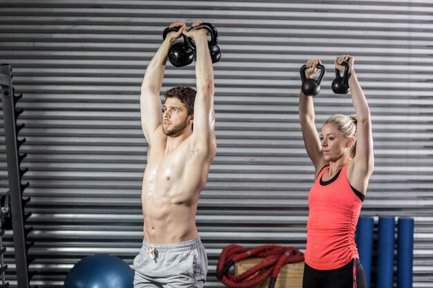 Couple soulevant des haltères ensemble au gymnase de crossfit