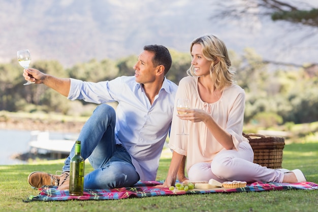 Couple souriant, assis sur une couverture de pique-nique et profiter de la vue