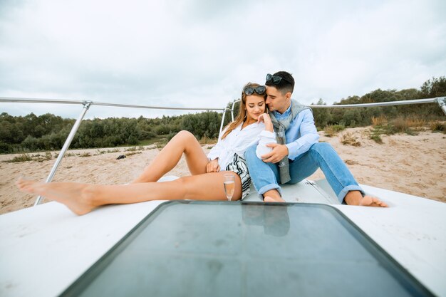 Couple souriant assis et parlant sur le pont du yacht