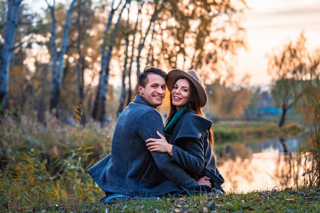 Le couple souriant assis près du lac
