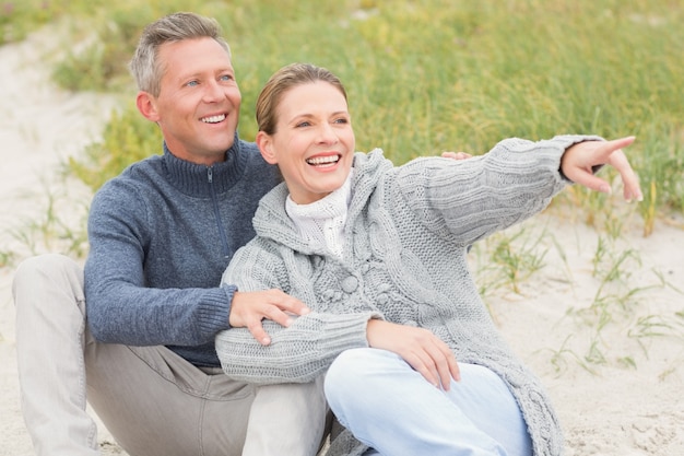 Couple souriant, assis sur le sable