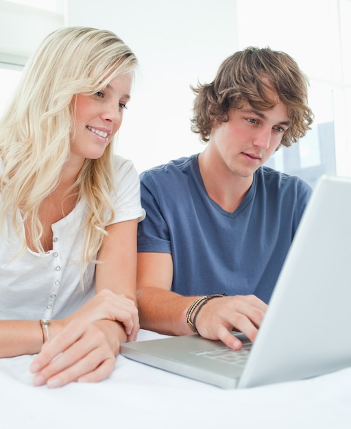 Un couple souriant assis et utilisant l&#39;ordinateur portable