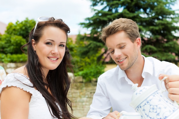 Couple souriant, boire du café dans le jardin