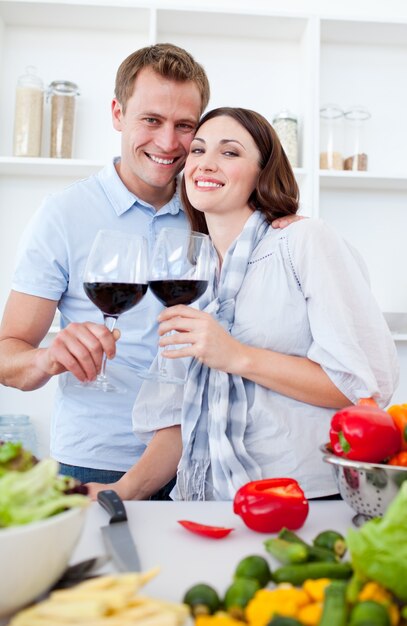 Couple souriant, boire du vin pendant la cuisson